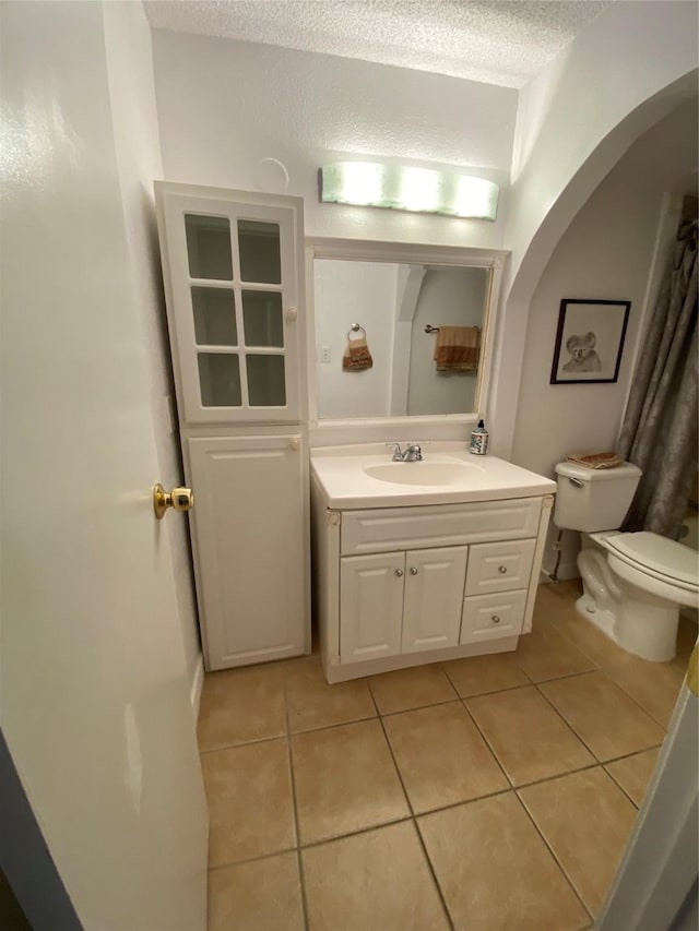 full bath with tile patterned floors, toilet, vanity, and a textured ceiling