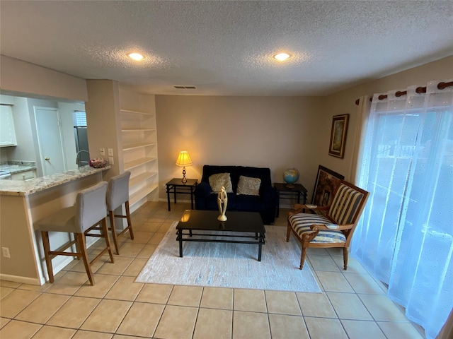living room featuring a textured ceiling, light tile patterned floors, recessed lighting, and built in features