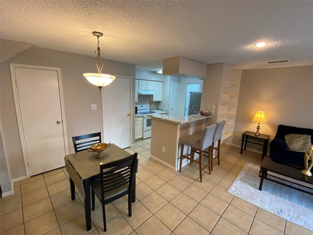 dining room featuring a textured ceiling, light tile patterned floors, and baseboards