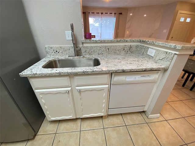 kitchen with dishwasher, a sink, light tile patterned floors, a peninsula, and white cabinetry