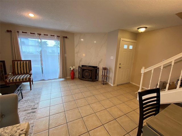 living area featuring a textured ceiling, light tile patterned flooring, baseboards, recessed lighting, and stairs