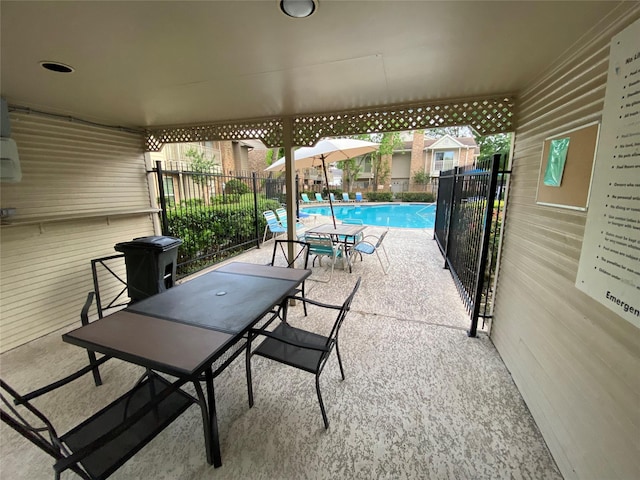 view of patio featuring a community pool, fence, and outdoor dining space