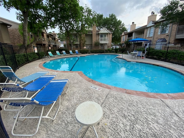 community pool with fence, a patio area, and a residential view