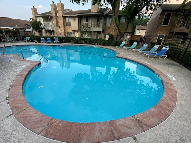 community pool with fence and a patio area