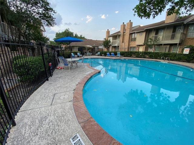 community pool with fence and a patio area