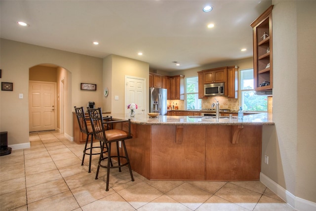1634 Topaz Trl, Willis, TX 77378 - kitchen featuring appliances with stainless steel finishes, arched walkways, recessed lighting, stone counters, and brown cabinets