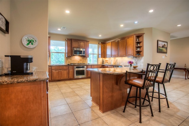 1634 Topaz Trl, Willis, TX 77378 - kitchen featuring stainless steel appliances, a peninsula, decorative backsplash, a kitchen bar, and recessed lighting