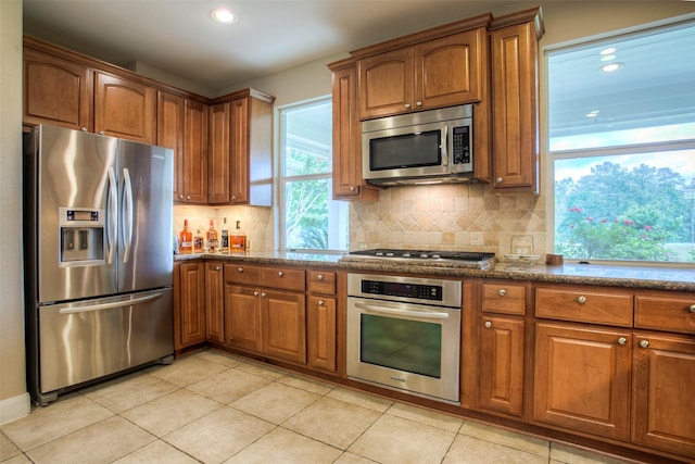 1634 Topaz Trl, Willis, TX 77378 - kitchen with stainless steel appliances, brown cabinetry, backsplash, and recessed lighting