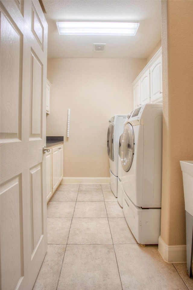 1634 Topaz Trl, Willis, TX 77378 - laundry area with washing machine and clothes dryer, cabinet space, light tile patterned floors, and baseboards