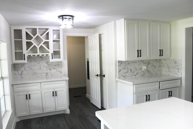 213 Red Haven Dr, Highlands, TX 77562 - kitchen with backsplash, light stone countertops, glass insert cabinets, dark wood-type flooring, and white cabinets