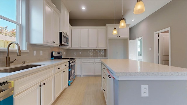 153 Treasure Dr, Houston, TX 77076 - kitchen featuring appliances with stainless steel finishes, a sink, tasteful backsplash, a kitchen island, and white cabinets