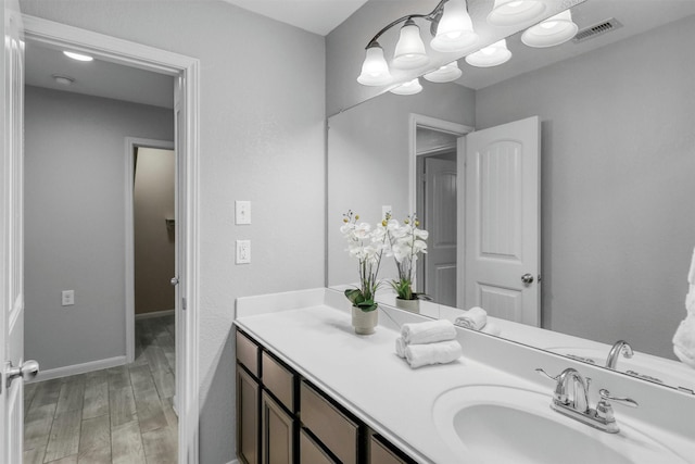 bathroom featuring vanity, baseboards, visible vents, and wood finished floors