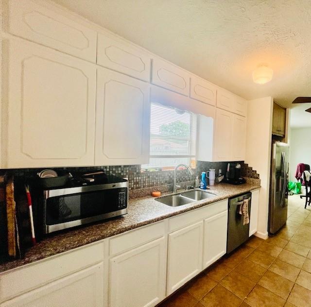 2122 Clemson Dr, Katy, TX 77493 - kitchen with a sink, stainless steel appliances, white cabinets, tile patterned flooring, and backsplash
