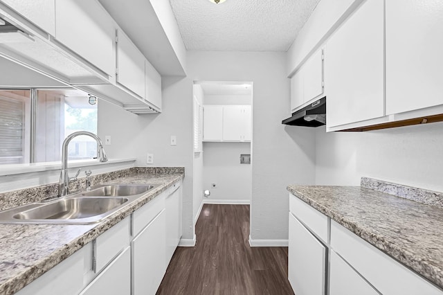kitchen featuring a textured ceiling, dark wood finished floors, white cabinetry, and a sink