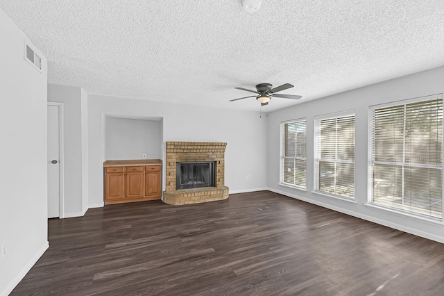 unfurnished living room featuring a ceiling fan, a fireplace, a textured ceiling, baseboards, and dark wood-style floors