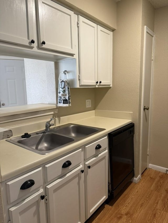 kitchen with light wood-style flooring, dishwasher, a sink, white cabinetry, and light countertops