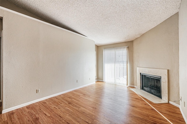 unfurnished living room with a textured ceiling, a textured wall, a fireplace with flush hearth, and wood finished floors