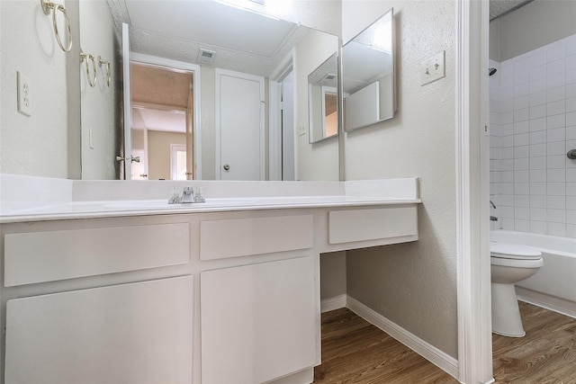 bathroom with toilet, wood finished floors, vanity, visible vents, and tub / shower combination