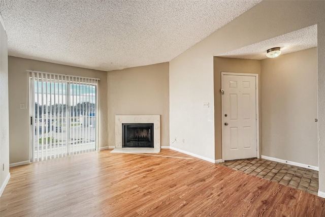 unfurnished living room with a premium fireplace, light wood finished floors, a textured ceiling, and baseboards