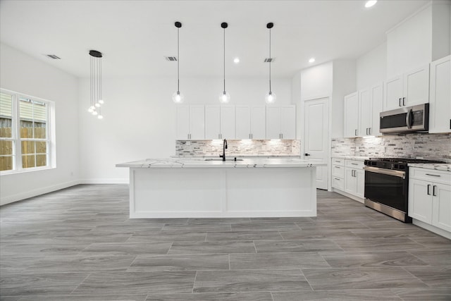 10935 Brookeshire Chase Ln, Houston, TX 77043 - kitchen with gas range oven, stainless steel microwave, tasteful backsplash, a center island with sink, and white cabinets