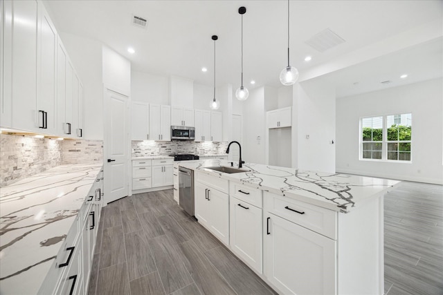10935 Brookeshire Chase Ln, Houston, TX 77043 - kitchen with a sink, appliances with stainless steel finishes, decorative backsplash, light stone counters, and recessed lighting