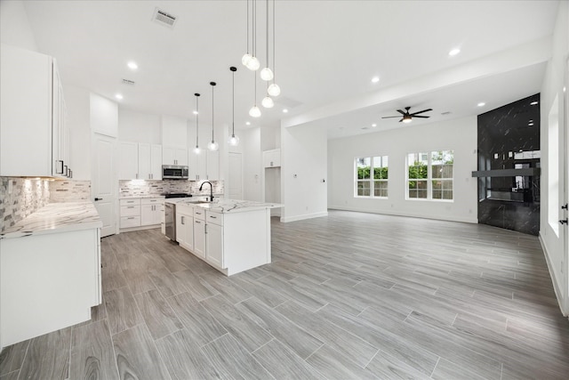 10935 Brookeshire Chase Ln, Houston, TX 77043 - kitchen with stainless steel appliances, a sink, a ceiling fan, backsplash, and white cabinets