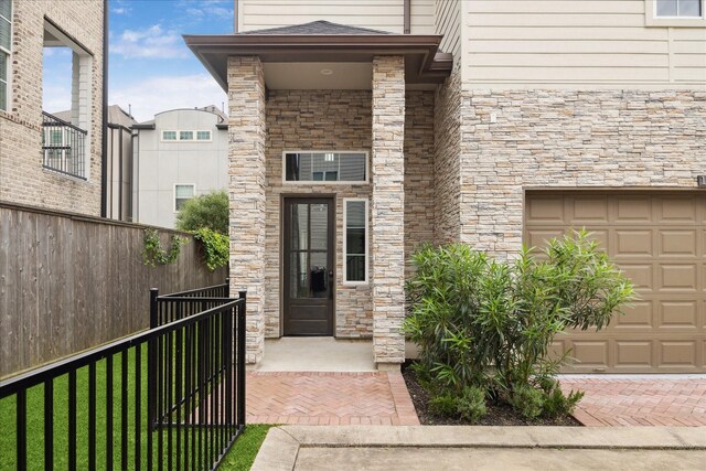 10935 Brookeshire Chase Ln, Houston, TX 77043 - view of exterior entry with stone siding, a garage, and fence
