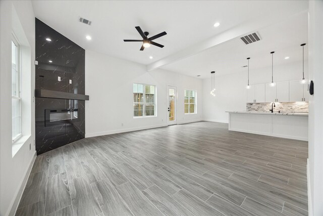 10935 Brookeshire Chase Ln, Houston, TX 77043 - unfurnished living room with a ceiling fan, baseboards, light wood-type flooring, recessed lighting, and a sink