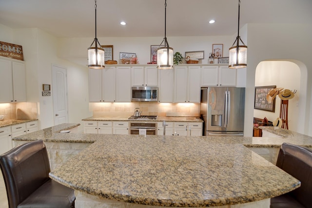 4803 Birch Grove Dr, Fulshear, TX 77441 - kitchen with stainless steel appliances, arched walkways, decorative backsplash, white cabinetry, and a kitchen breakfast bar