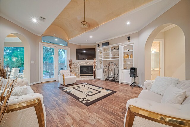 122 Marble Staff Ct, Houston, TX 77069 - living room featuring crown molding, wood finished floors, a stone fireplace, arched walkways, and lofted ceiling