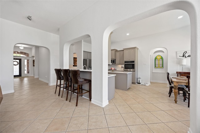 15306 Clearhaven Ct, Cypress, TX 77429 - kitchen featuring stainless steel appliances, a breakfast bar, light tile patterned flooring, light countertops, and gray cabinets