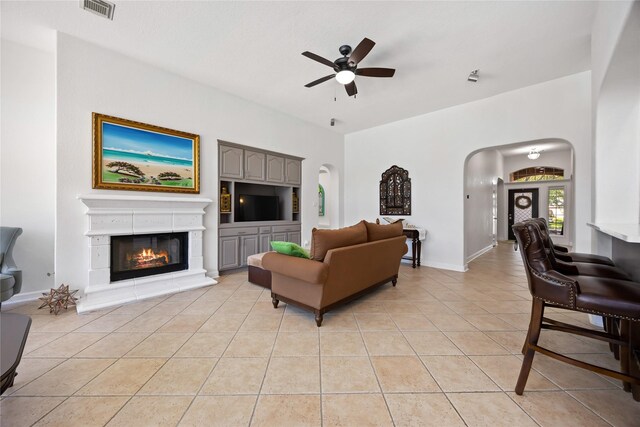 15306 Clearhaven Ct, Cypress, TX 77429 - living area with light tile patterned flooring, visible vents, arched walkways, a ceiling fan, and a glass covered fireplace