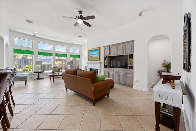 15306 Clearhaven Ct, Cypress, TX 77429 - living room with visible vents, a fireplace, ceiling fan, arched walkways, and light tile patterned floors