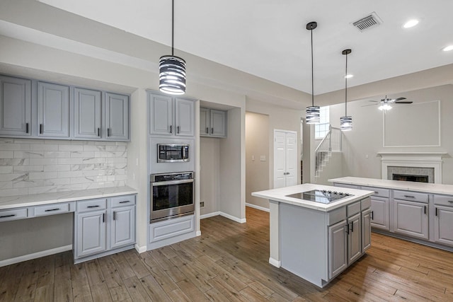 kitchen with gray cabinetry, ceiling fan, visible vents, a kitchen island, and appliances with stainless steel finishes