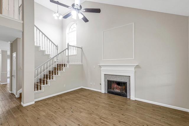 unfurnished living room with baseboards, high vaulted ceiling, a ceiling fan, and wood finished floors