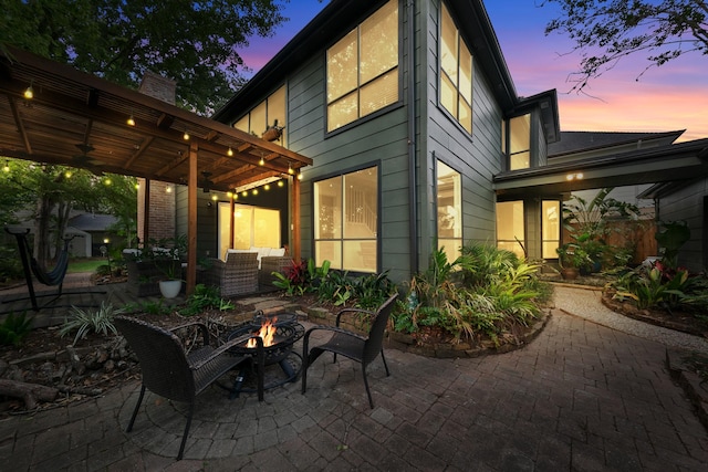 rear view of house featuring a patio, a ceiling fan, a fire pit, and a chimney