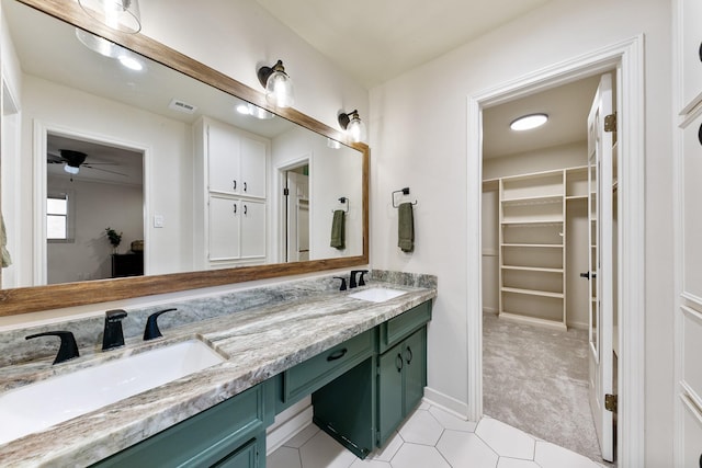full bathroom featuring a spacious closet, tile patterned flooring, double vanity, a ceiling fan, and baseboards