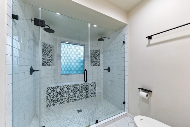 bathroom featuring a shower stall, toilet, and tile patterned flooring