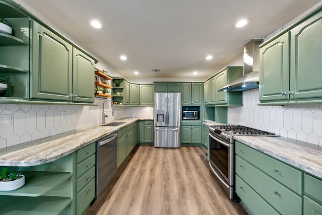 kitchen featuring open shelves, appliances with stainless steel finishes, wall chimney range hood, green cabinets, and recessed lighting