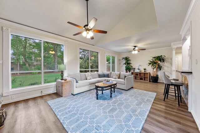 living room featuring ceiling fan, vaulted ceiling, wood finished floors, and crown molding