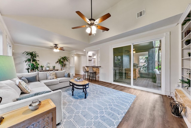 living area with a ceiling fan, wood finished floors, crown molding, lofted ceiling, and baseboards