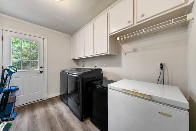 laundry area with washing machine and clothes dryer, cabinet space, ornamental molding, and light wood-style floors