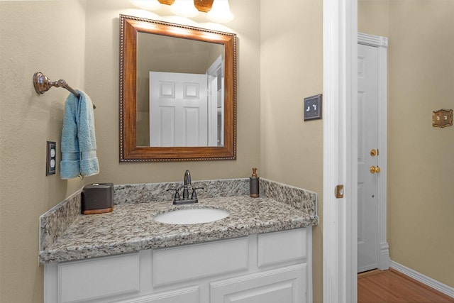 bathroom featuring baseboards, wood finished floors, and vanity
