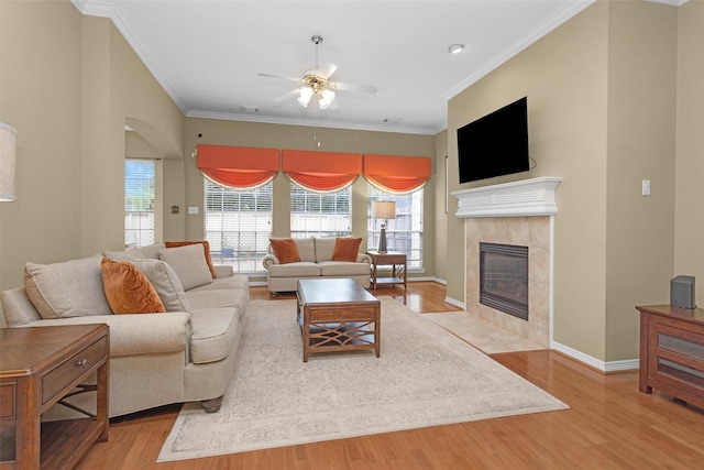 living area with a fireplace, ceiling fan, a wealth of natural light, and light wood-style floors