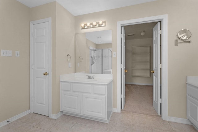 full bathroom featuring tile patterned floors, a stall shower, baseboards, and vanity