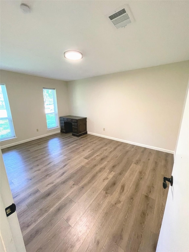 empty room featuring baseboards, visible vents, and wood finished floors