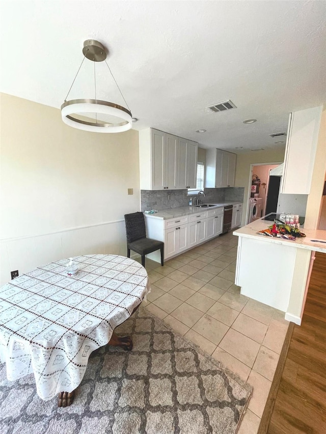 kitchen with a sink, visible vents, white cabinetry, light countertops, and light tile patterned floors