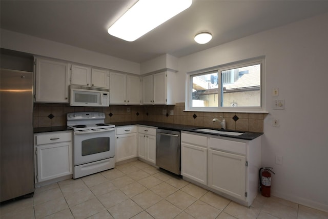7521 Beaudelaire Cir, Galveston, TX 77551 - kitchen with appliances with stainless steel finishes, a sink, dark countertops, decorative backsplash, and light tile patterned floors