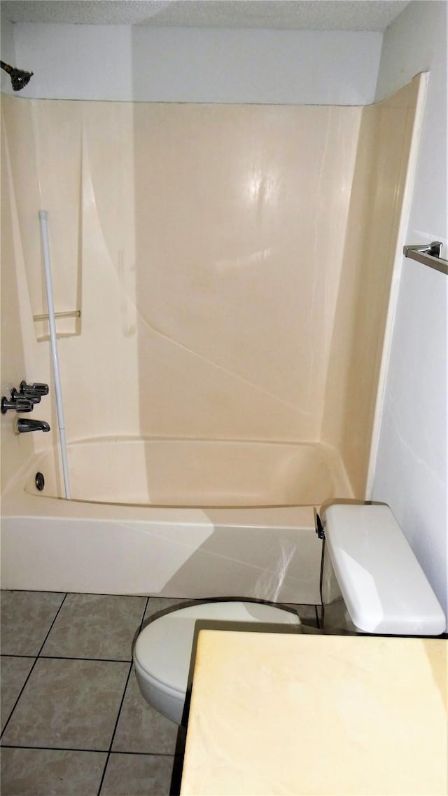 bathroom with toilet,  shower combination, and tile patterned flooring