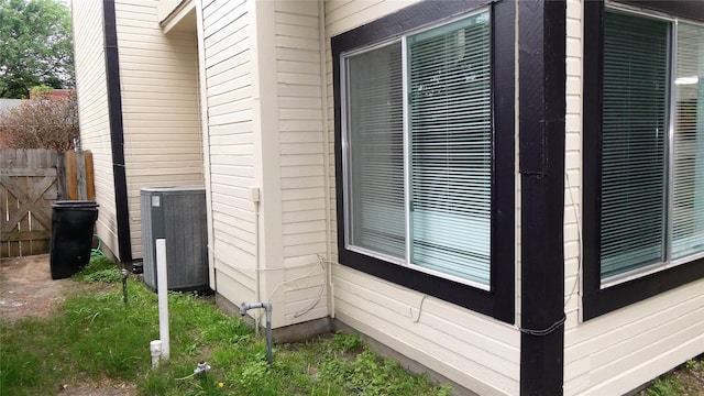 view of home's exterior with central air condition unit and fence